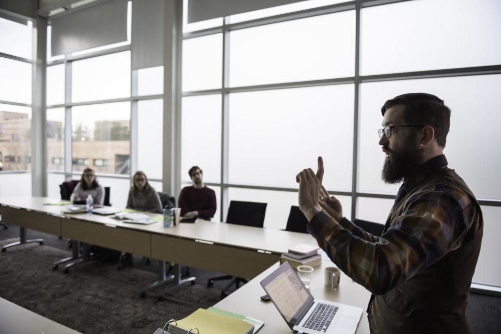 A graduate student teachers in front of a classroom